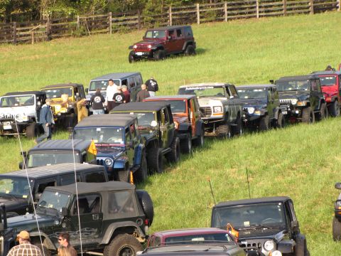 1979 Ford Bronco - A white Ford Bronco is visible in a line of off-road vehicles parked on a grassy hill.