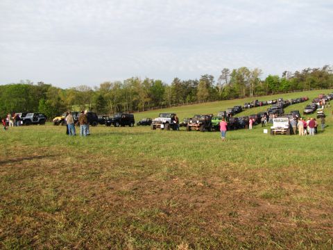 1979 Ford Bronco - A large gathering of off-road vehicles parked in a field on a cloudy day.