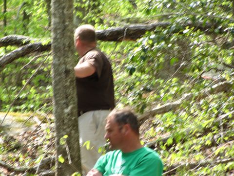 1979 Ford Bronco - Two men are in a wooded area, with one partially obscured by a tree trunk.