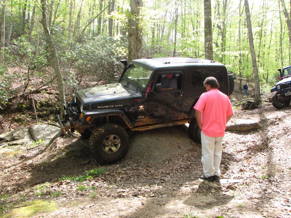 Black Jeep Wrangler Rubicon navigating an off-road trail with a person watching