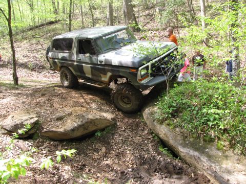 1979 Ford Bronco - This camouflaged Ford Bronco is tackling a challenging off-road course in the woods.