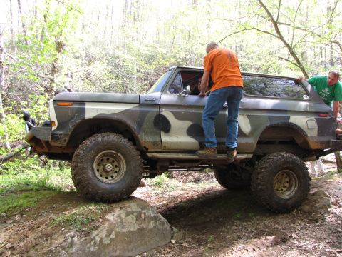 1979 Ford Bronco - This camouflaged Ford Bronco appears to be from 1978, seen here navigating rough terrain with assistance from two individuals.