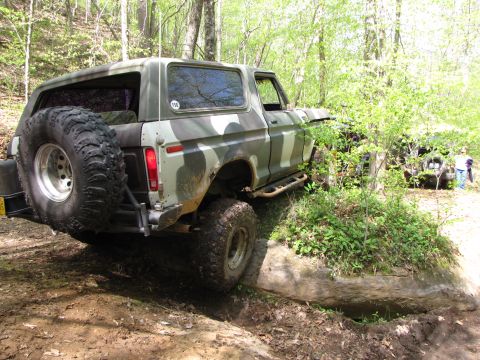 1979 Ford Bronco - A camouflaged Ford Bronco navigates a challenging off-road trail with another vehicle visible in the background.