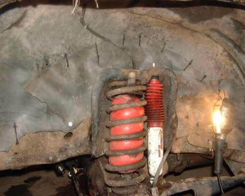 1985 Ford F-150 - Close-up of the front wheel well area of a 1985 Ford F-150, showing red air shocks and a Rancho RS 5000 shock absorber.