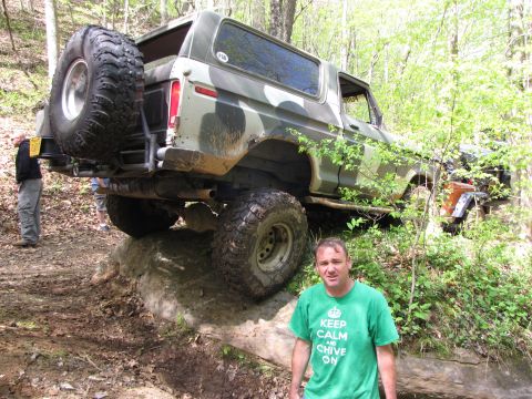 1979 Ford Bronco - Camouflaged Ford Bronco navigating a difficult off-road obstacle. Another vehicle is partially visible behind it.