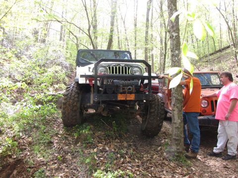 1979 Ford Bronco - Two Jeeps navigate a wooded trail, one in front with a winch and brush guard.