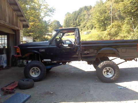 1995 Ford F-150 - This black 1995 Ford F-150 pickup truck features a solid axle (SAS) swap, giving it a lifted appearance.