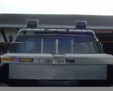 1985 Ford F-150 - The rear of a truck is shown, a diamond plate toolbox and a light bar mounted above the cab.