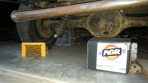 2005 Ford Mustang - Underside view of a vehicle's rear axle and exhaust, with a wheel chock and a product box.