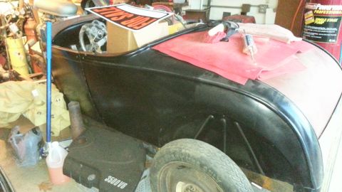 2005 Ford Mustang - A black hot rod is parked indoors with a "FOR SALE" sign visible on a box behind the steering wheel.