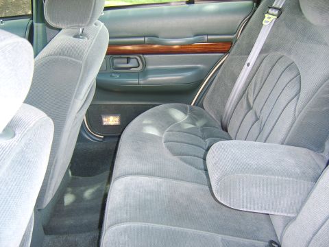 1996 Mercury Grand Marquis - The rear interior of a 1996 Mercury Grand Marquis, grey velour seats and wood trim accents on the door panels.