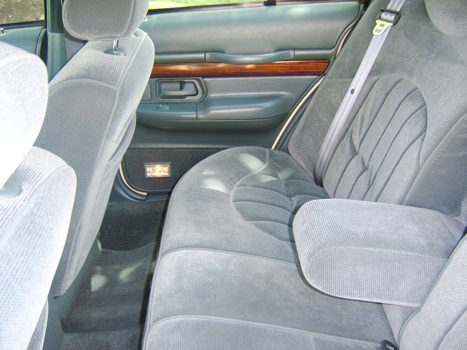 Gray cloth rear bench seat and woodgrain door panel in a full-size sedan