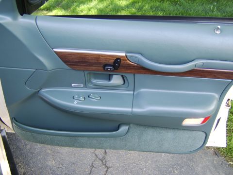 1996 Mercury Grand Marquis - The interior door panel of a 1996 Mercury Grand Marquis features wood trim and power window and seat controls.