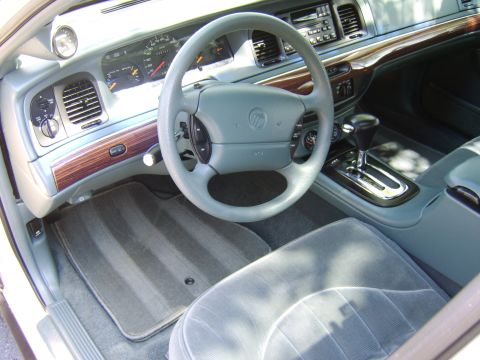 1996 Mercury Grand Marquis - The interior of a car, the dashboard, steering wheel, and front seats with wood grain accents.