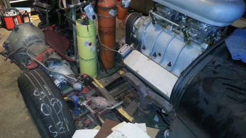 2005 Ford Mustang - Various automotive parts, including a supercharged engine and transmission, are piled together in a workshop.
