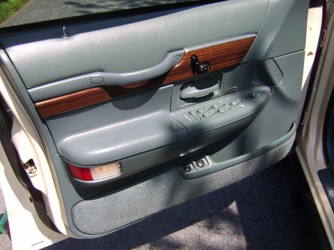 1996 Mercury Grand Marquis - Interior door panel of a 1996 Mercury Grand Marquis, gray upholstery, wood trim accents, and power window controls.