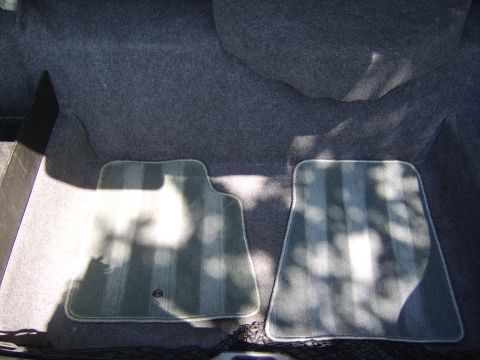 1996 Mercury Grand Marquis - The interior of a car trunk shows gray carpeting and two striped floor mats.