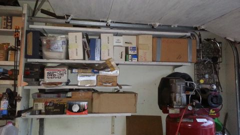 2005 Ford Mustang - Shelving units are filled with various boxes and containers, alongside a red air compressor in a garage setting.