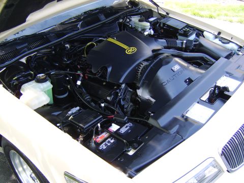 1996 Mercury Grand Marquis - The engine bay of a beige car, a V8 engine and a distinctive yellow AG emblem on the air intake cover.