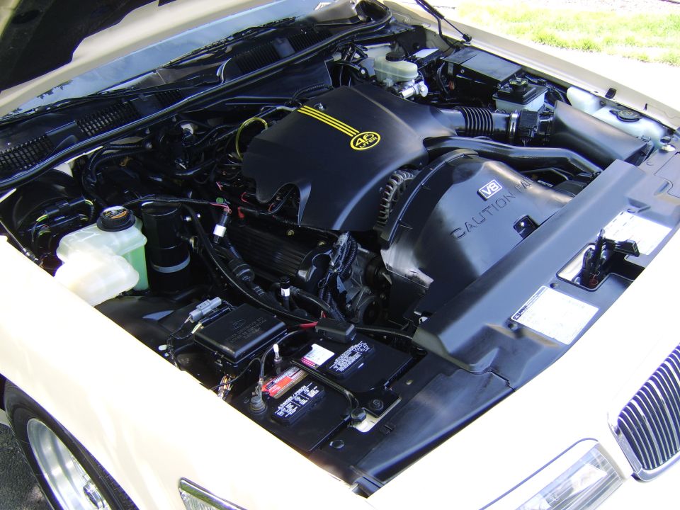 Cream Mercury sedan engine bay with 4.6 liter V8, coolant bottle and battery