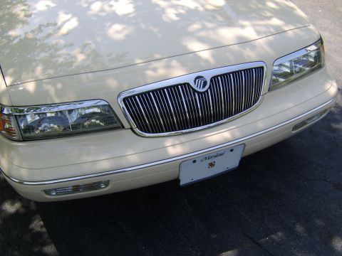 1996 Mercury Grand Marquis - The front of a cream-colored sedan shows a prominent chrome grille and headlights, with a Maryland license plate.
