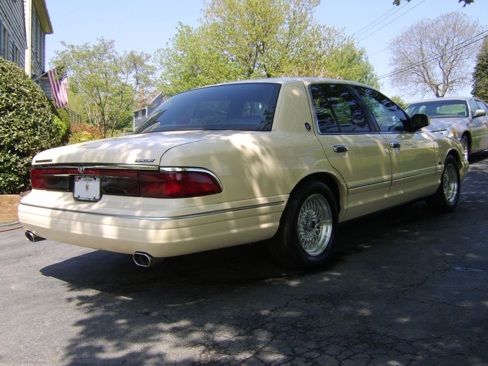 Cream Mercury Grand Marquis sedan rear 3/4 view with dual chrome exhaust tips