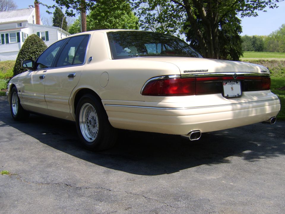 Cream Mercury Grand Marquis sedan, driver-side rear 3/4 view on driveway