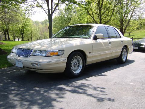 1996 Mercury Grand Marquis - A cream 1996 Mercury Grand Marquis is parked outdoors, with another vehicle visible in the background.