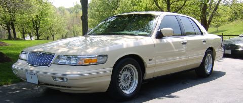 1996 Mercury Grand Marquis - Cream 1996 Mercury Grand Marquis parked outside with trees and grass in the background.