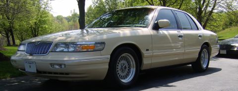 1996 Mercury Grand Marquis - A tan 1996 Mercury Grand Marquis is parked outside on a sunny day.