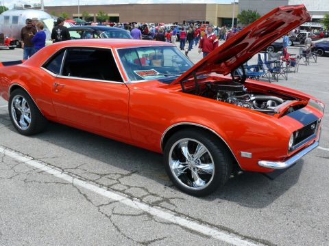 1968 Chevrolet Camaro - A classic orange muscle car is parked with its hood open, revealing the engine bay.
