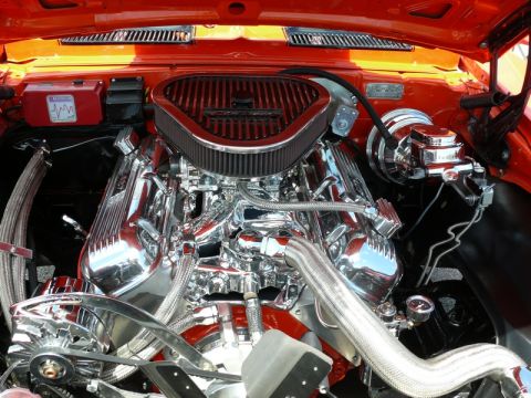 1968 Chevrolet Camaro - Detailed view of a polished V8 engine in an orange 1968 Chevrolet Camaro, highlighting chrome components and the air intake system.