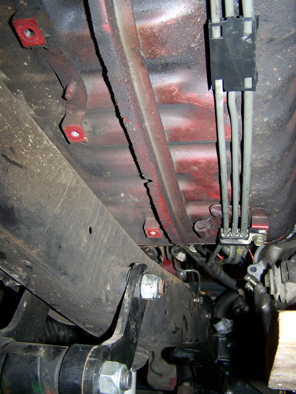 Undercarriage of a vehicle with red painted frame rails and brake lines