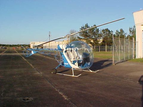 1992 Ford Bronco - A blue and white helicopter sits on an asphalt pad near a building and a chain-link fence.