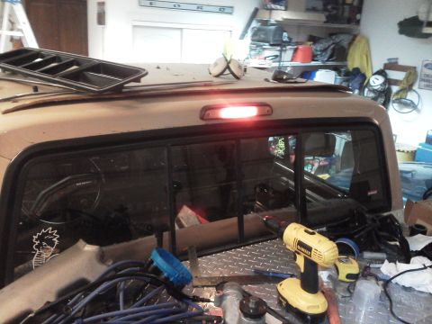 1979 Ford F-150 - The rear of a truck is shown with a third brake light illuminated, surrounded by various tools and automotive parts.