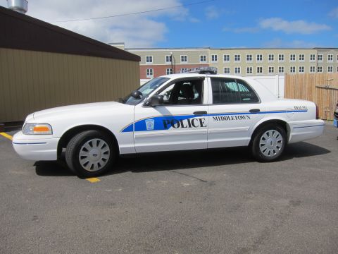 1991 Ford LTD Crown Victoria - white Middletown Police sedan marked POLICE with a blue stripe parked in a paved lot beneath a partly cloudy sky.