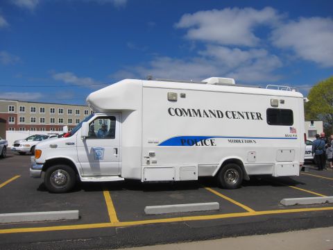 1991 Ford LTD Crown Victoria - Side view of a white police Command Center RV marked POLICE Middletown with a blue stripe parked across striped parking spaces.