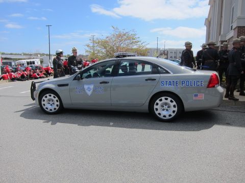 1991 Ford LTD Crown Victoria - silver Rhode Island State Police sedan parked on pavement with uniformed officers and motorcycles assembled in the background.