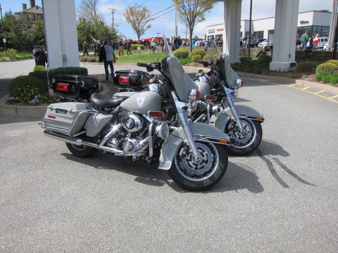 1991 Ford LTD Crown Victoria - pair of silver police touring motorcycles with saddlebags and windshields parked together on pavement near an event crowd.