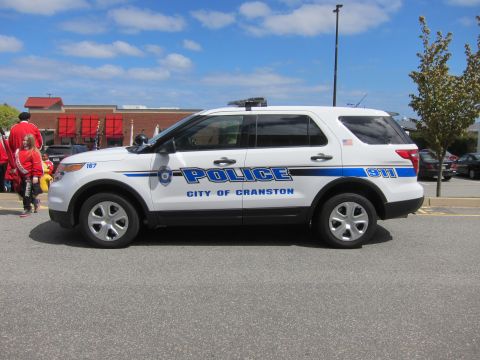1991 Ford LTD Crown Victoria - white City of Cranston Police Ford Explorer SUV photographed in profile with people in red shirts visible in the background.