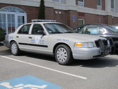 1991 Ford LTD Crown Victoria - silver Rhode Island State Police Ford Crown Victoria sedan with a front push bar parked beside a brick building.