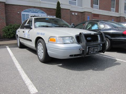 1991 Ford LTD Crown Victoria - silver State Police Ford Crown Victoria with a heavy front push bar and a state-issue license plate parked by a brick building.