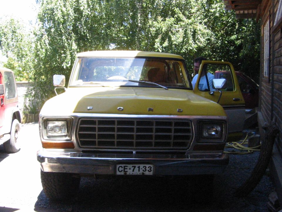 Yellow 1979 Ford Bronco with a chrome grille and square headlights, parked next to a red Jeep