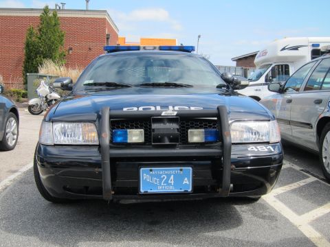 1991 Ford LTD Crown Victoria - black police Ford Crown Victoria photographed head-on, showing its push bar, light bar and a Massachusetts police plate reading 24.