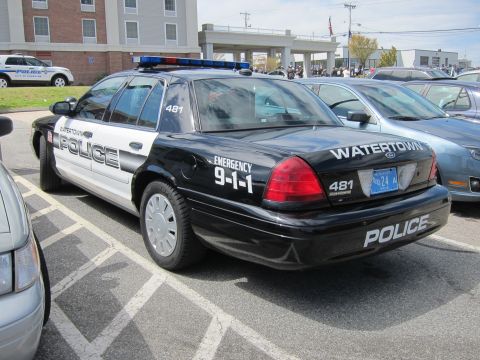 1991 Ford LTD Crown Victoria - black-and-white Watertown Police Ford Crown Victoria cruiser shown from the rear quarter among other vehicles at an event.