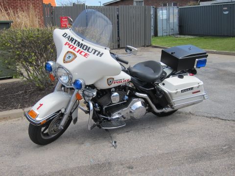 1991 Ford LTD Crown Victoria - white Dartmouth Police Harley-Davidson touring motorcycle with a fairing, saddlebags and rear top case parked near a fence.