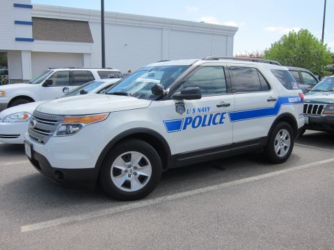 1991 Ford LTD Crown Victoria - white Ford Explorer SUV marked U S NAVY POLICE with blue striping parked among other vehicles.