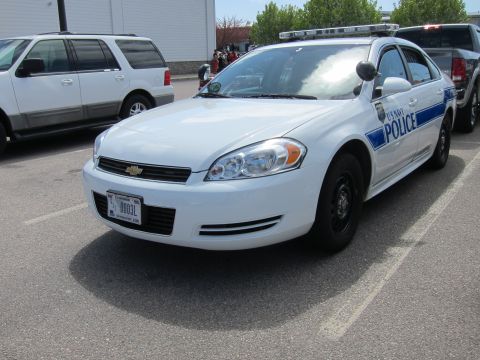 1991 Ford LTD Crown Victoria - Front three-quarter view of a white Chevrolet Impala marked U S NAVY POLICE with blue striping and steel wheels.