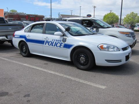 1991 Ford LTD Crown Victoria - white Chevrolet Impala marked U S NAVY POLICE with blue striping parked in a lot near an Applebees restaurant.