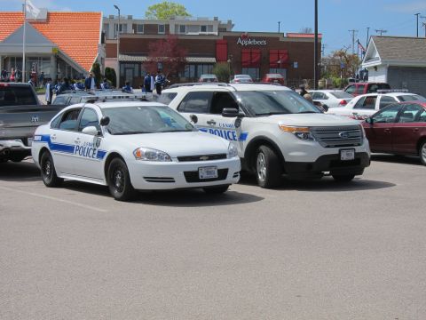 1991 Ford LTD Crown Victoria - white U S Navy Police Chevrolet Impala and a white Ford police SUV parked side by side in a lot near an Applebees.